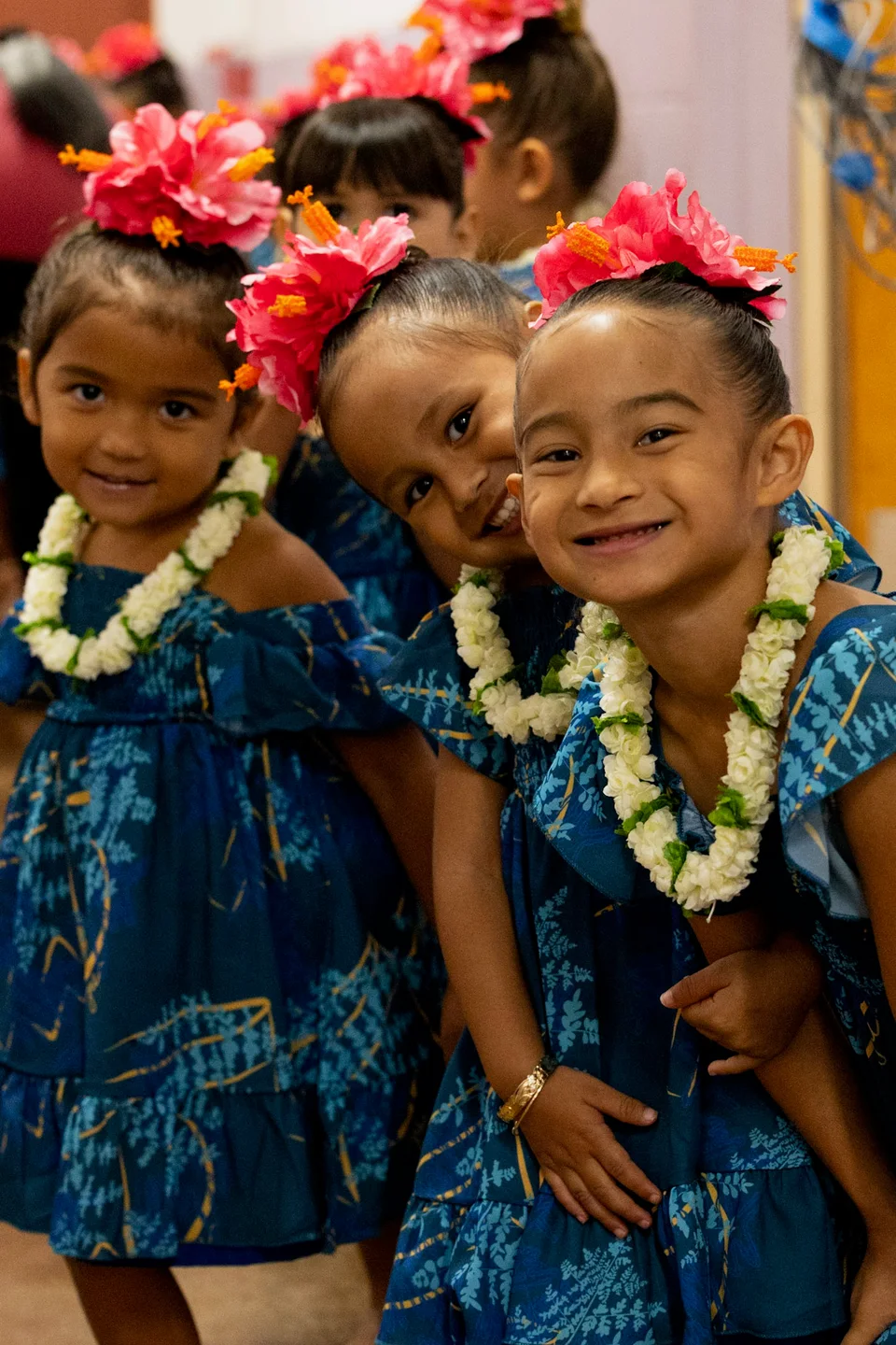 Keiki smiling together in blue dresses and flower lei.