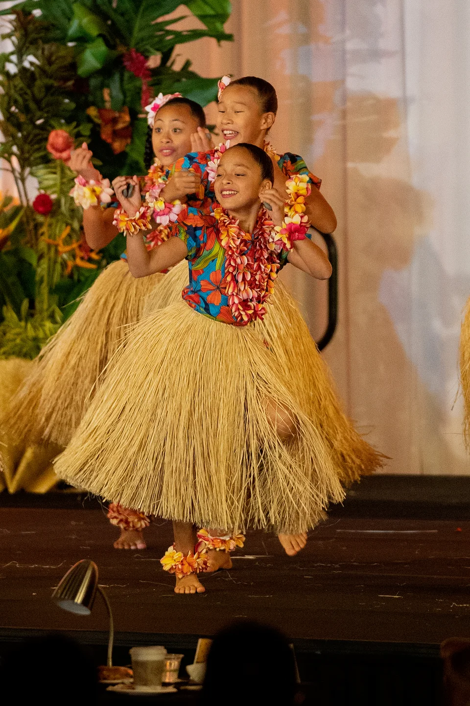 Keiki performing in floral tops, lei, and natural-colored skirts.